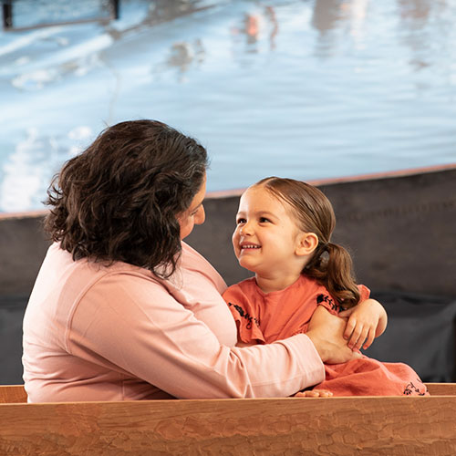 smiling child sitting on woman's lap