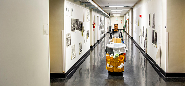 Custodian rolling cart down hallway